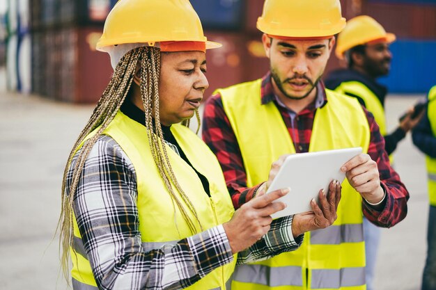 Foto trabajadores multirraciales que controlan contenedores de envío en el puerto industrial al aire libre enfoque en la cara de la mujer mayor africana