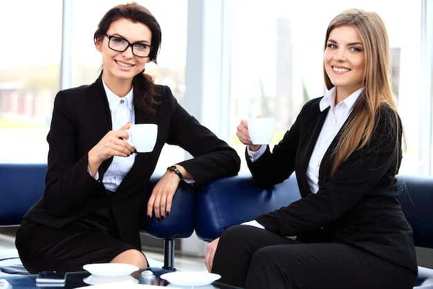 Los trabajadores de oficina en la pausa para el café, la mujer disfruta charlando con sus colegas, sonriendo