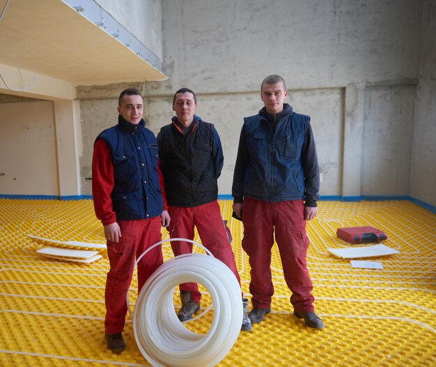 Foto trabajadores que instalan un sistema de calefacción por suelo