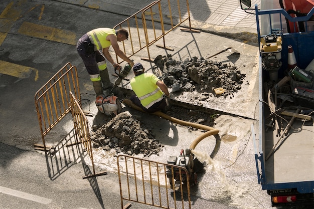 Trabajadores reparando una tubería de agua rota en la carretera