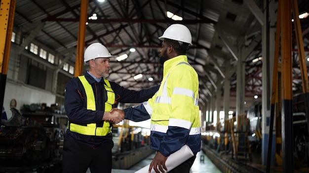 Trabajadores reunidos en ingenieros de la industria de la fábrica de ingeniería estrechando la mano sobre un acuerdo comercial