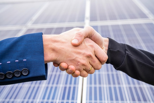 Los trabajadores con ropa de trabajo se saludan de la mano antes de comenzar a trabajar en paneles solares