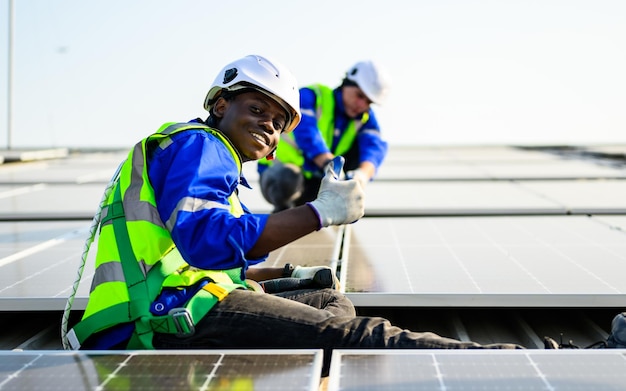 Trabajadores técnicos con uniforme de seguridad que comprueban paneles fotovoltaicos