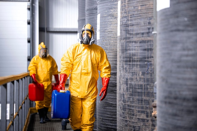 trabajadores con traje amarillo hazmat, máscaras antigás y guantes que manipulan productos químicos o sustancias peligrosas