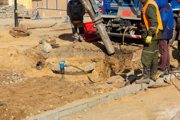 Los trabajadores usan una excavadora de succión basada en un camión para tomar muestras de suelo en un pozo para comunicaciones