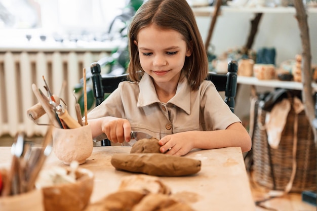 Trabajando con arcilla La niña está aprendiendo a hacer cerámica en el taller