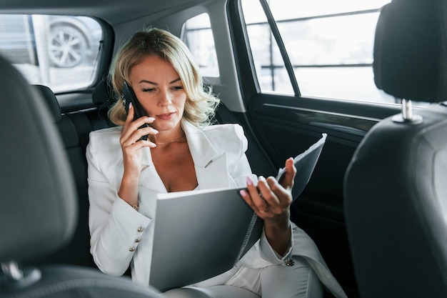 Trabajando en el auto Mujer en ropa formal está adentro en el autosalon