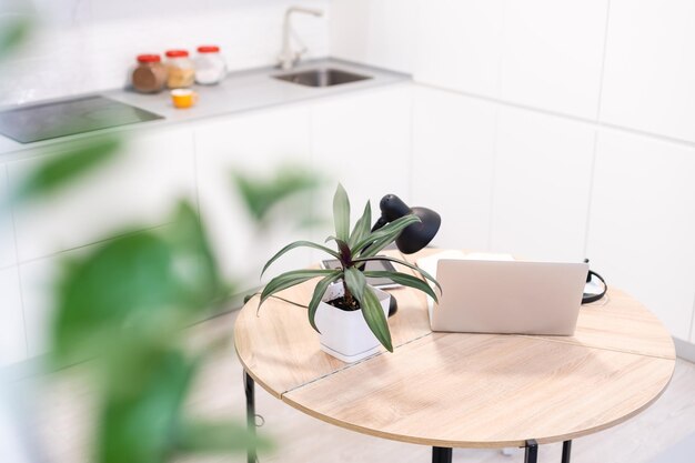 Trabajando desde casa: una computadora portátil y un organizador en una mesa de cocina con cocina al fondo.