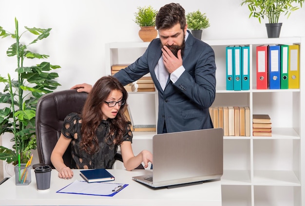 Trabajando desde cualquier lugar Los compañeros de trabajo serios usan la computadora del trabajo Trabajo de oficina Jefe y secretaria en el lugar de trabajo Hombre y mujer de carrera Ejecutando ebusiness