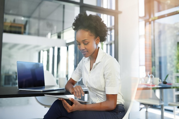 Trabajando duro para lograr el éxito Captura recortada de una joven empresaria que trabaja en una tableta digital en una oficina moderna