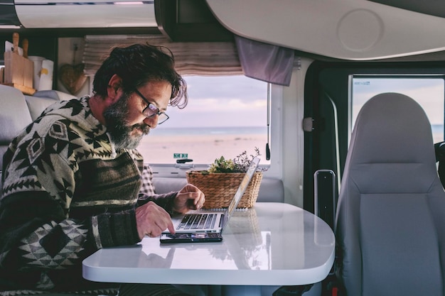 Trabajando fuera de la red en una oficina alternativa y un concepto de estilo de vida de trabajo en línea hombre Las personas adultas trabajan en una computadora portátil dentro de una autocaravana autocaravana Trabajo inteligente en el transporte de vehículos de viaje Usando un portátil