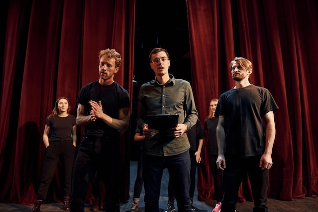 Trabajando juntos Grupo de actores con ropa de color oscuro ensayando en el teatro