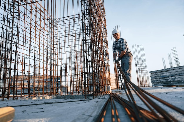 Trabajando con material metálico El hombre está en el sitio de construcción durante el día