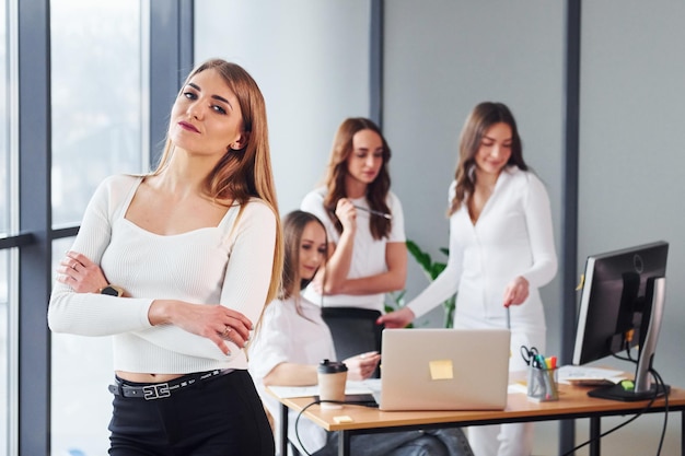 Trabajando por mesa con laptop Grupo de mujeres adultas que con ropa formal están juntas en la oficina