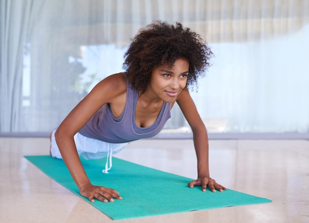 Trabajando en la parte superior del cuerpo Foto de una atractiva joven haciendo flexiones en una colchoneta de ejercicios