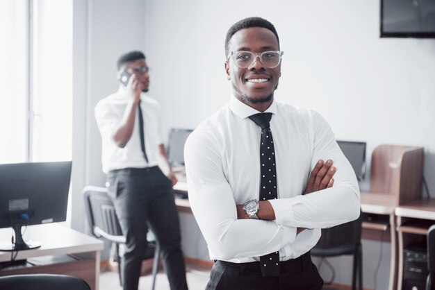 Trabajando con una sonrisa. Heerful empresario africano de pie delante de colega.