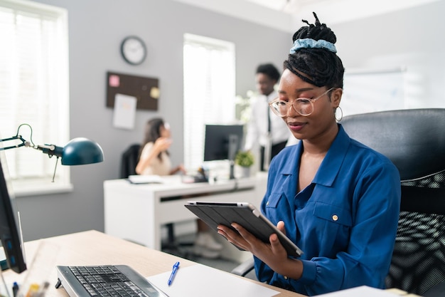 Trabajando en tareas corporativas de oficina elegante hermosa mujer ambiciosa sentada en el escritorio con tableta