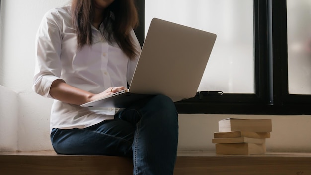 Trabajando usando una computadora portátil en la mesa de madera Manos escribiendo en un teclado