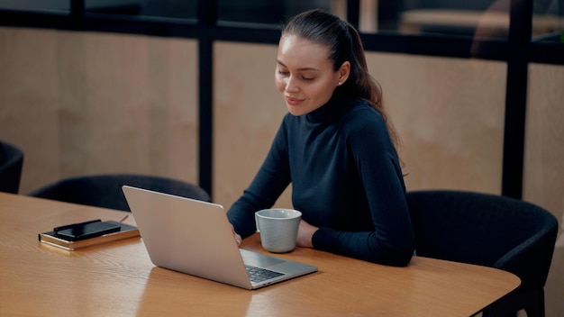 Trabajar en un administrador de computadoras portátiles es una mujer Lugar de trabajo en una oficina de coworking en alquiler por