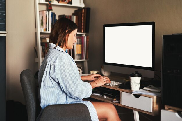 Trabajar desde casa es mi foto favorita Recortada de una atractiva joven empresaria sentada sola en la oficina de su casa y usando su computadora