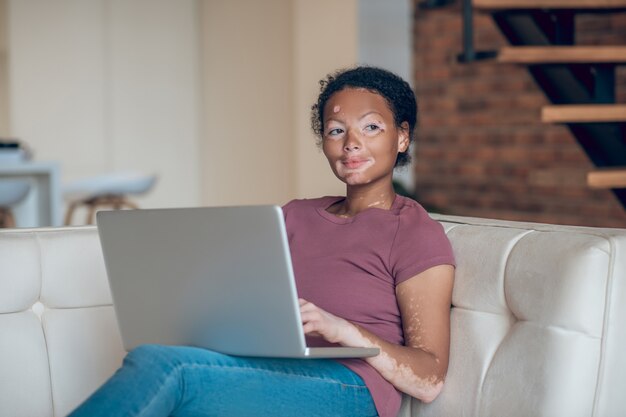 Trabajar desde casa. Linda mujer joven trabajando en una computadora portátil y mirando pensativo