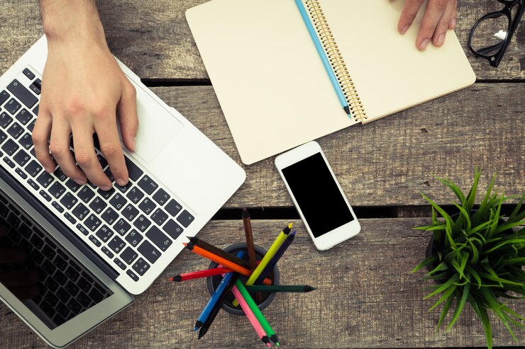 Foto trabajar en un escritorio de madera con un teléfono inteligente portátil y papelería de colores en un entorno casual