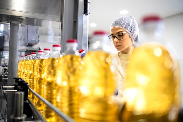 Trabajar en la industria alimentaria comprobando la producción de aceite vegetal embotellado