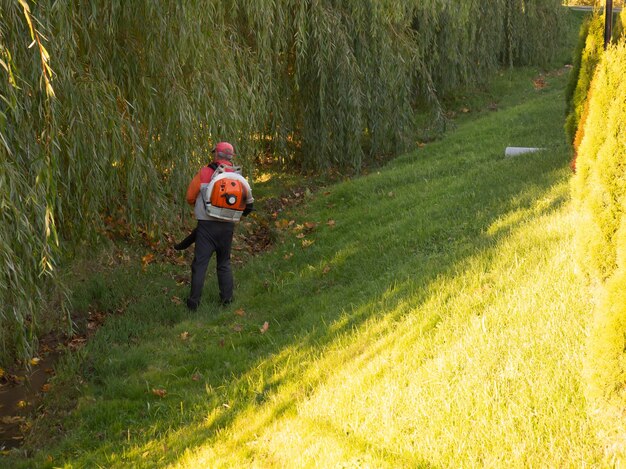 Trabajar en el parque quita las hojas de otoño con un soplador