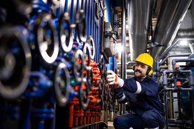 Foto trabajar en refinería cerrando válvulas industriales y manteniendo la presión de las tuberías de distribución