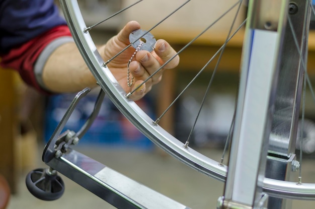 Trabajar en un taller de reparación de bicicletas mide el grosor de los radios