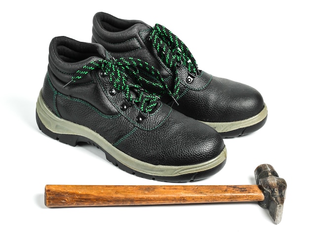 Trabajar zapatos de cuero y martillo sobre un fondo blanco. Control de fuerza, seguridad del trabajador
