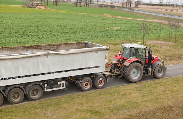 Trabajo agrícola en la cosecha de heno con maquinaria agrícola Tractor con remolque en el campo