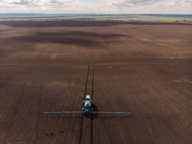 Trabajo agrícola de primavera en los campos el tractor rocía cultivos con herbicidas, insecticidas y pesticidas