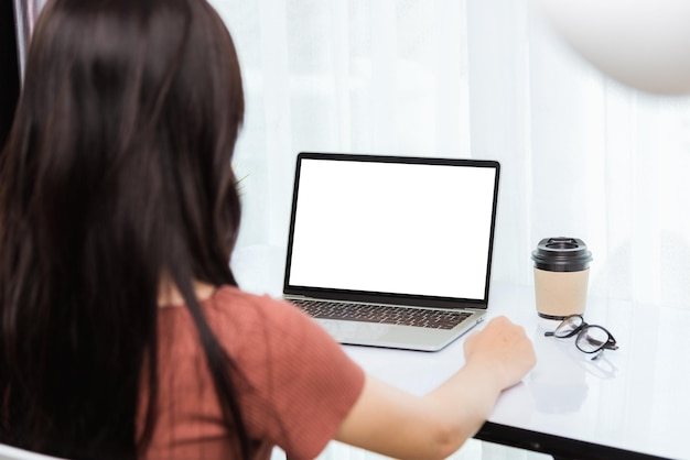 El trabajo desde casa, la videoconferencia de la parte posterior de una joven empresaria asiática o una reunión presencial en línea en la computadora portátil frontal pone en cuarentena el coronavirus de la enfermedad o COVID-19 en la oficina del hogar