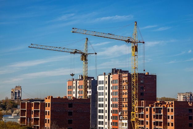 Trabajo en curso en un nuevo bloque de apartamentos Edificio alto en construcción con grúas Sitio de construcción de un nuevo edificio