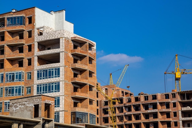 Trabajo en curso en un nuevo bloque de apartamentos Edificio alto en construcción con grúas Sitio de construcción de un nuevo edificio