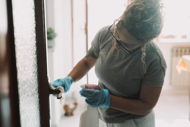 Trabajo doméstico en casa Una mujer limpiando la puerta en el apartamento con spray y guantes Trabajo de ama de casa Higiene y desinfección del lugar de vida Criada trabajando y limpiando las superficies de la casa Concepto de saludable