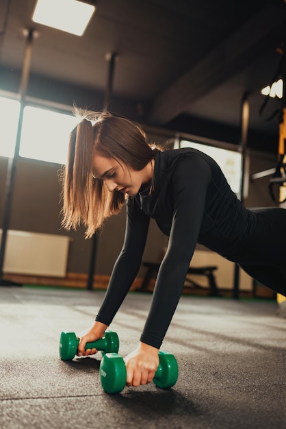 Trabajo duro femenino en el gimnasio con flexiones de pesas. Mujer fuerte en el gimnasio.