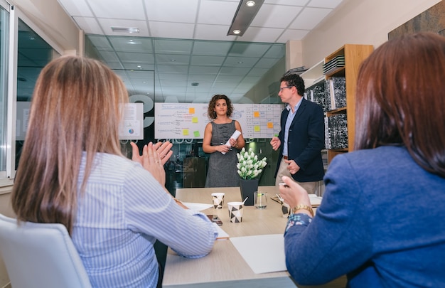 Trabajo en equipo aplaudiendo a la mujer jefa en una reunión para celebrar el éxito de un proyecto empresarial en la sede