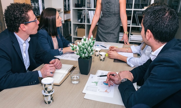 Trabajo en equipo en busca de empresaria irreconocible en una reunión alrededor de la mesa en la sede de la empresa