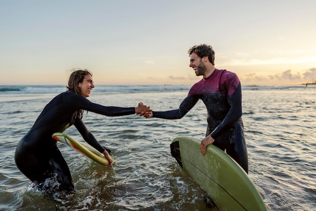 Foto trabajo en equipo y concepto de apoyo surfistas en el agua cogidos de la mano