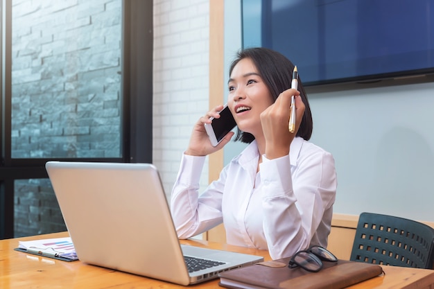 Trabajo en equipo de la empresaria que usa el teléfono inteligente para contactarse con el compañero.