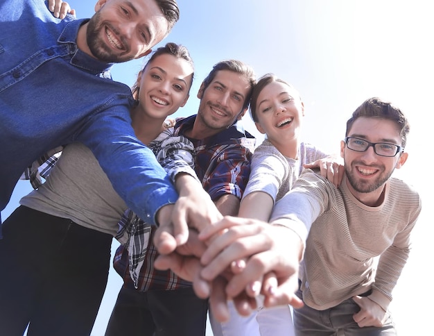 Trabajo en equipo de los estudiantes universitarios que apila concepto de la mano