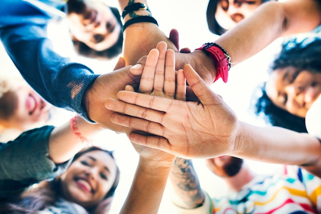 Trabajo en equipo de los estudiantes universitarios que apila concepto de la mano