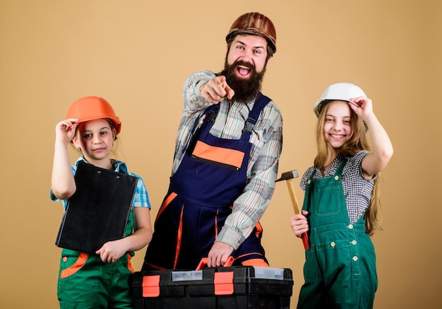 Trabajo en equipo familiar Reparación Hombre barbudo con niñas pequeñas asistente de trabajador de la construcción Constructor o carpintero Reparador en uniforme Ingeniero Padre e hija en el taller Rompiendo estereotipos