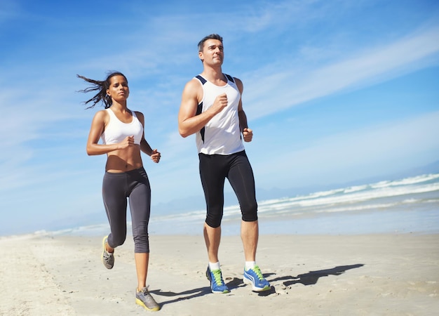 Trabajo en equipo de fitness o pareja en la playa corriendo para entrenamiento de ejercicio o entrenamiento al aire libre en el mar deportistas corredores o atletas sanos en la naturaleza para cardio resistencia bienestar o desafío en la arena