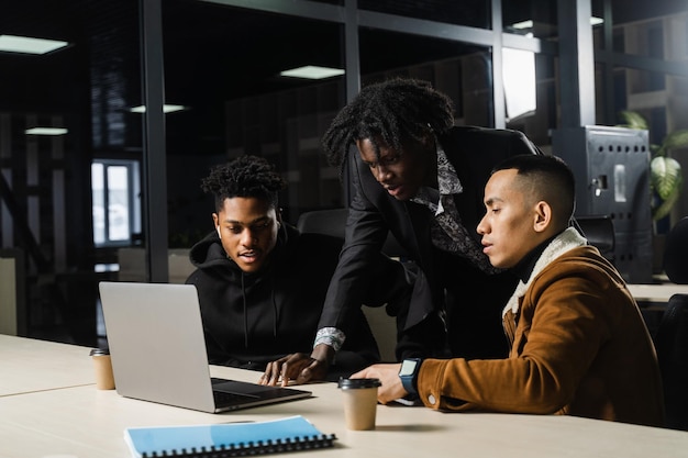 Trabajo en equipo de grupos multiétnicos de empleados negros africanos y asiáticos que trabajan juntos en una computadora portátil Discutir el proceso de negocios en equipo en la oficina