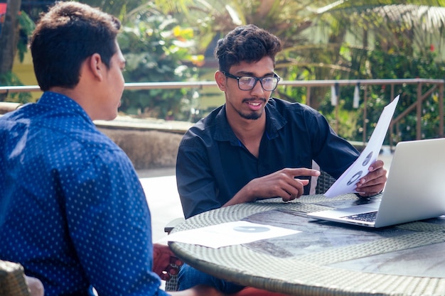 Trabajo en equipo hombres indios guapos y exitosos en una elegante computadora portátil de trabajo independiente bien vestida en la playa estudiante de negocios de trabajo remoto independiente en un café de verano en la costa del océano indio