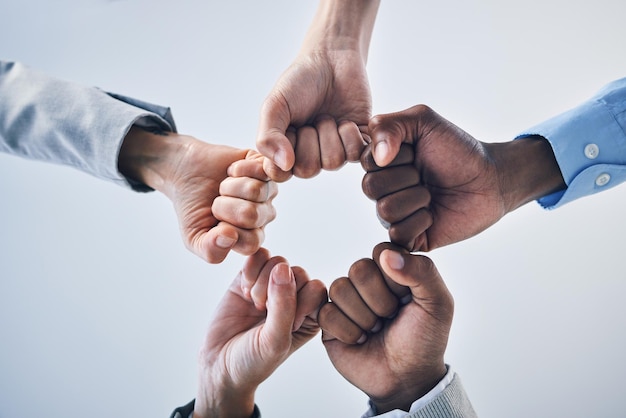 Trabajo en equipo motivación y colaboración puño golpe manos gesto signo o icono debajo en estudio pared fondo maqueta Diversidad grupo de trabajadores o empresarios juntos en unidad solidaridad y esfuerzo