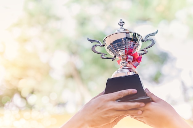 Trabajo en equipo profesional que sostiene la taza del trofeo que celebra con la concesión del trofeo